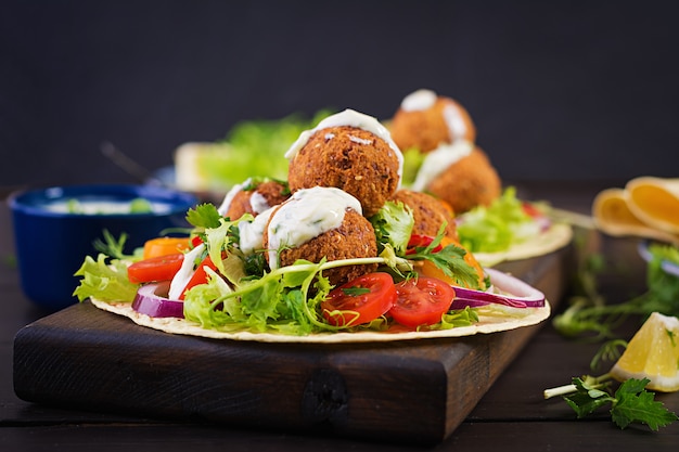 Avvolgere la tortilla con falafel e insalata fresca. Tacos Vegani. Cibo vegetariano sano.