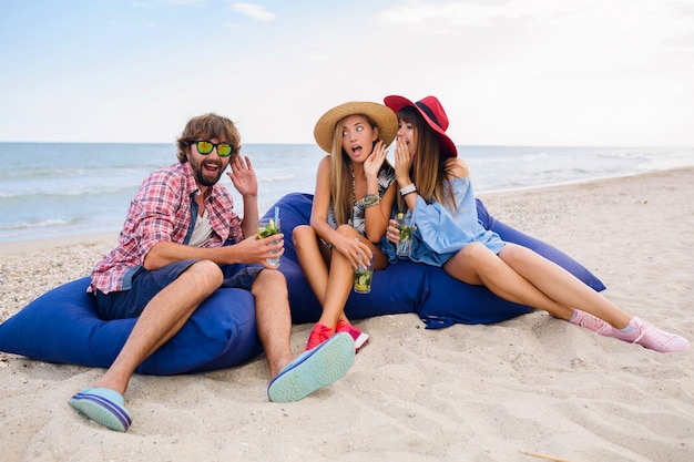 Azienda giovane hipster di amici in vacanza seduti in spiaggia sui sacchi di fagioli