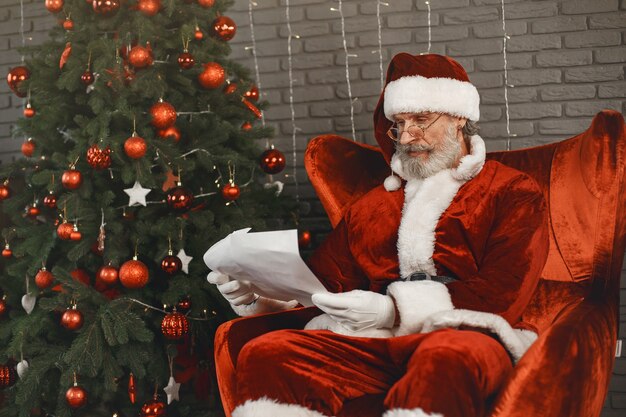 Babbo Natale che si riposa dall'albero di Natale. Decorazioni per la casa. Santa con la lettera dei bambini.