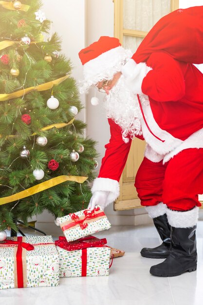 Babbo Natale mettendo regali sotto l&#39;albero di abete