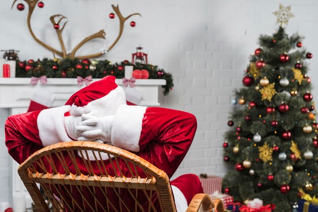 Babbo Natale seduto sulla sedia a dondolo con le mani dietro la testa