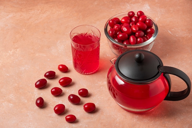 Bacche di corniolo nella tazza e succo nel bollitore.