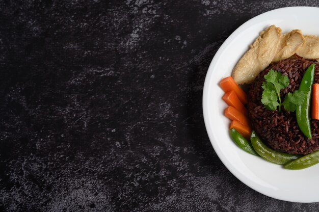 Bacche di riso viola cotte con petto di pollo grigliato. Zucca, carote e foglie di menta in un piatto, cibo pulito.