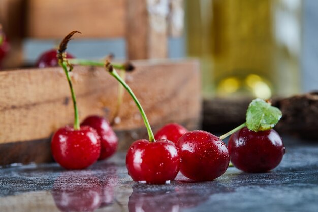 Bacche rosse succose della ciliegia su un tavolo blu