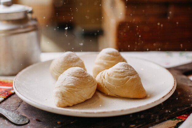 Badambura famoso dolce con noci tritate dolce riempito con zucchero a velo squisito all'interno del piatto bianco sulla scrivania in legno marrone durante il giorno