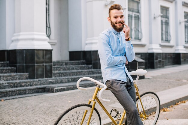 Baffi commoventi sorridenti dell&#39;uomo vicino alla bicicletta