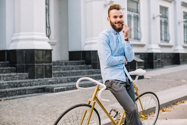 Baffi commoventi sorridenti dell&#39;uomo vicino alla bicicletta