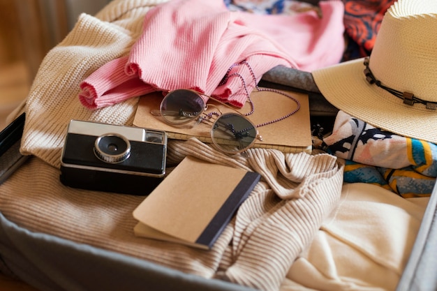 Bagaglio ad alto angolo con vestiti e macchina fotografica