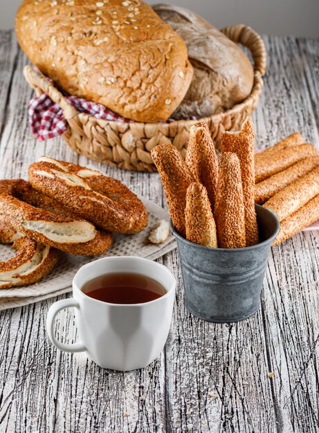 Bagel turco di vista laterale con una tazza di tè e pane su superficie di legno. verticale