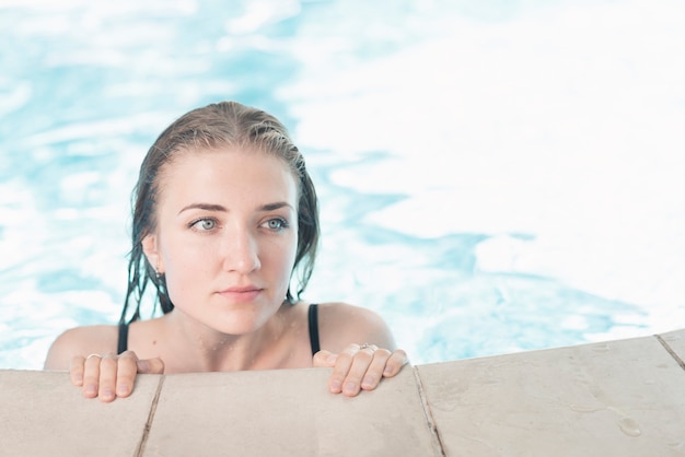 Bagnata bella giovane donna sul bordo della piscina