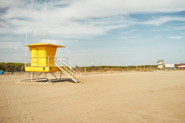 Foto gratuito bagnino giallo post onn spiaggia vuota