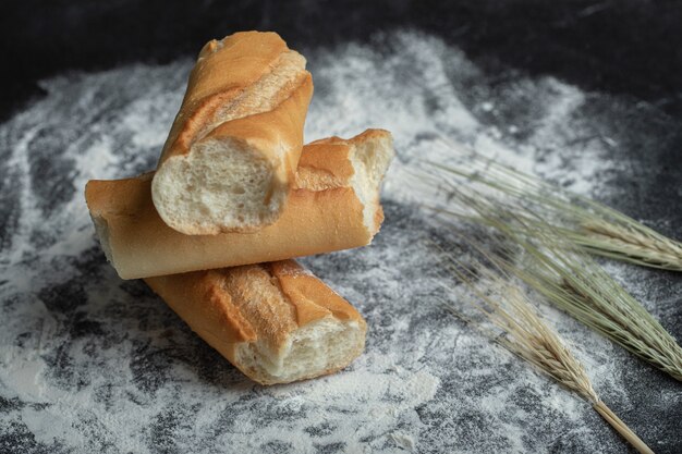 Baguette appena sfornate con orzo su sfondo bianco.