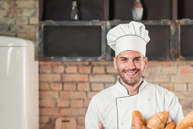 Baguette maschi sorridenti della tenuta del panettiere