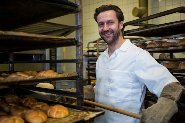 Baker mantenendo vassoio di panini cotti a scaffale