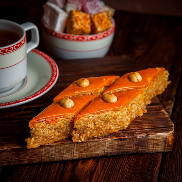 baklava con una tazza di tè e delizia turca in tavola di legno