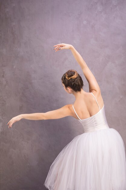 Ballerina di vista posteriore che posa con il fondo dello stucco