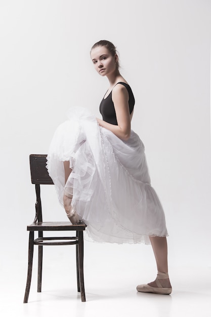 Ballerina teenager in gonna bianca che posa vicino alla sedia