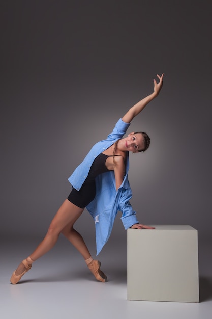 ballerino giovane bello stile moderno in posa sul cubo bianco su uno sfondo grigio di studio