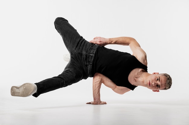 Ballerino maschio in canottiera e jeans facendo una mossa di danza