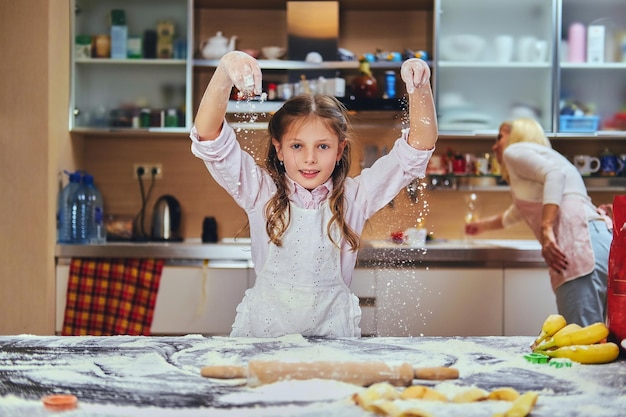 Bambina allegra che cucina pasta in cucina.