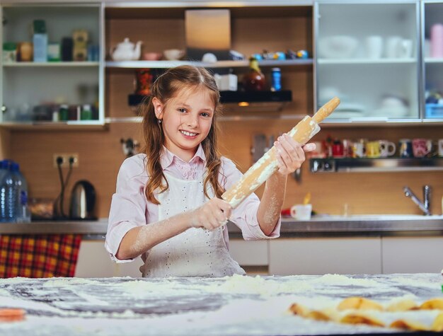 Bambina allegra che cucina pasta in cucina.