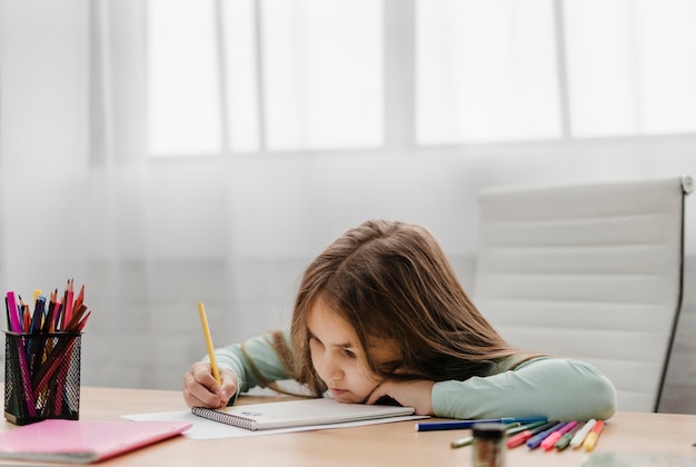 Bambina annoiata che prende appunti