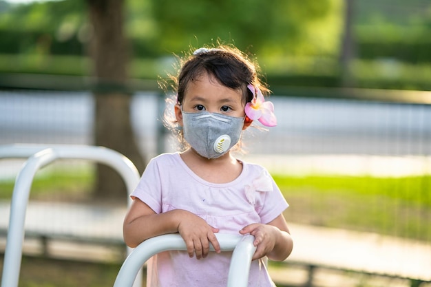 Bambina asiatica carina in una maschera protettiva all'aperto