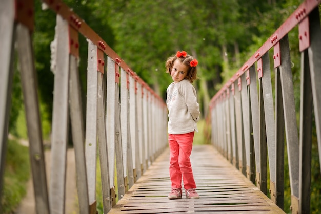 Bambina bella attraversando un ponte