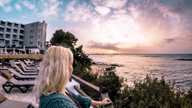 Bambina bionda che guarda il mare e il cielo serale sullo sfondo