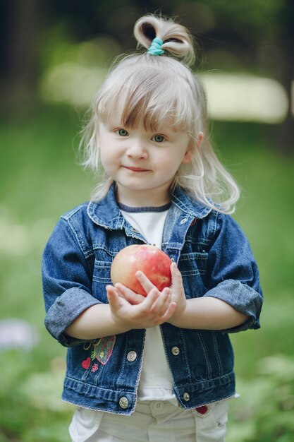 Bambina bionda che tiene una mela