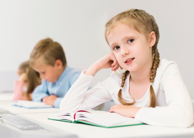 Bambina bionda seduta alla sua scrivania