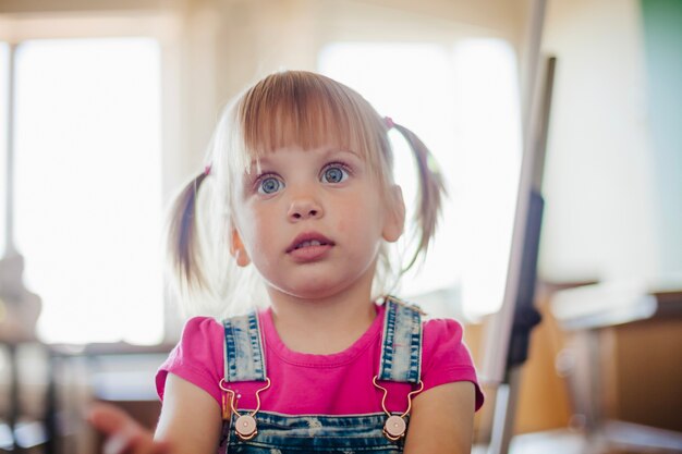 Bambina carina con gli occhi ampi che fissano