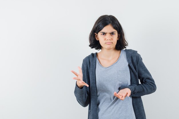 Bambina che allunga la mano nel gesto perplesso in t-shirt, giacca