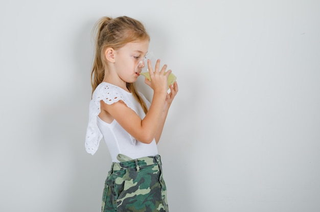 Bambina che beve il succo di frutta in maglietta bianca