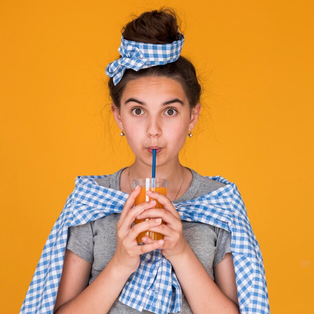 Bambina che beve un certo succo d'arancia