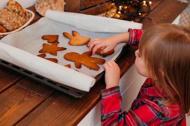 Bambina che controlla i biscotti di natale al forno