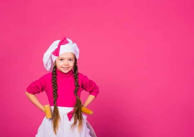 Bambina che cucina in piedi con utensili da cucina