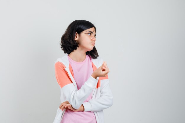 Bambina che fa gesto di soldi in t-shirt, giacca e che sembra bisognoso. vista frontale.