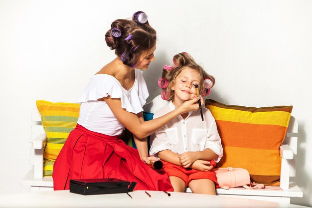 Bambina che gioca con il trucco di sua madre su bianco