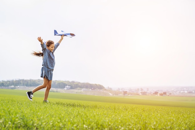 Bambina che gioca con l'aereo giocattolo nel campo