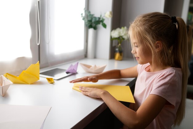 Bambina che gioca con la carta origami a casa