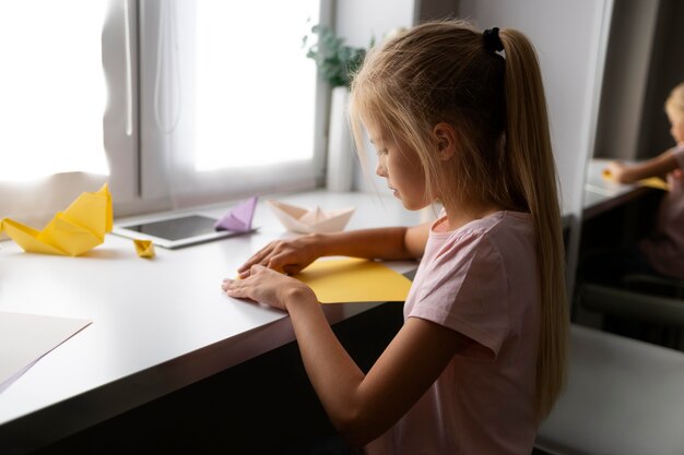 Bambina che gioca con la carta origami a casa