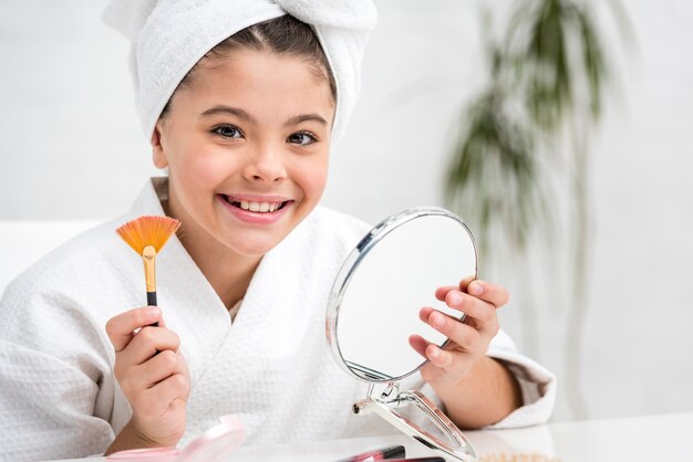 Bambina che gioca con la sua spazzola illuminatore di madri