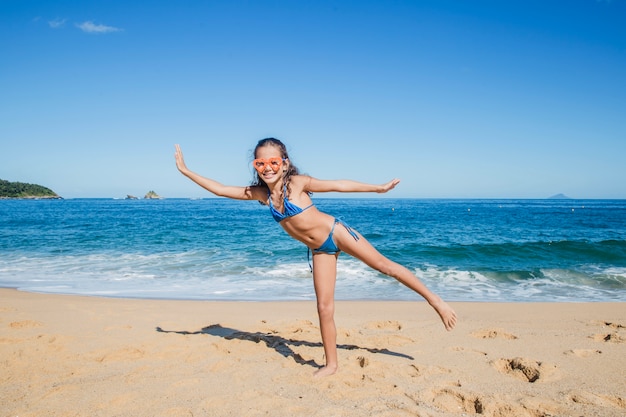 Bambina che gioca e che propone sulla spiaggia