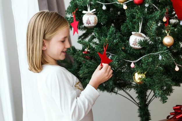 Bambina che gioca una stella rossa di albero di Natale