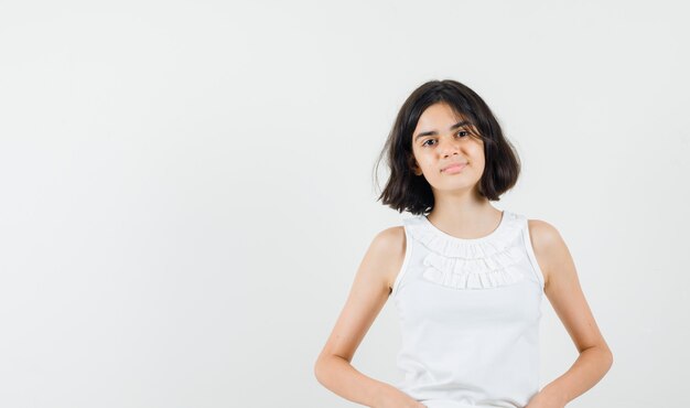 Bambina che guarda davanti in camicetta bianca e che sembra sensibile, vista frontale.