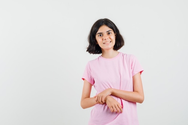 Bambina che guarda davanti in maglietta rosa e sembra carina, vista frontale.