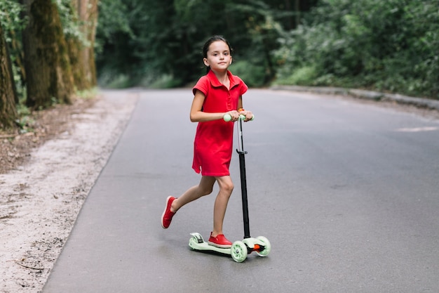 Bambina che guida il motorino di spinta sulla strada