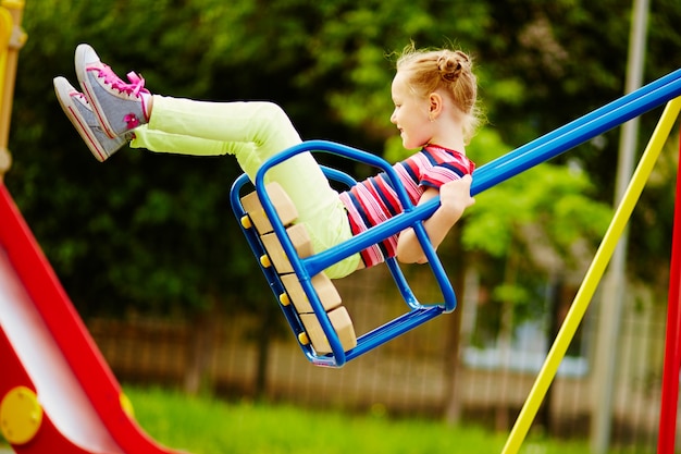 Bambina che ha divertimento su un&#39;oscillazione all&#39;aperto