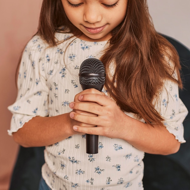 Bambina che impara a cantare a casa con il microfono